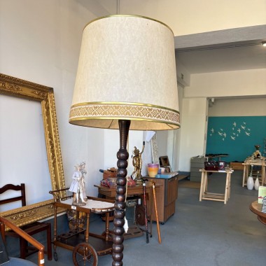 •	Candeeiro de pé, haste em madeira escura torneada e abajur cónico em tecido cru com acabamento dourado e uma faixa decorativa de inspiração clássica. 