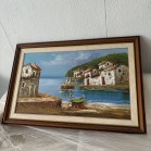Quadro a óleo, com imagem de um lugar á beira mar, rodeado de casas e barcos